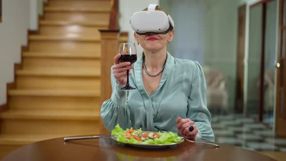 Medium Shot Portrait of Gorgeous Middle Aged Woman in VR Headset Smelling Expensive Red Wine Smiling alt