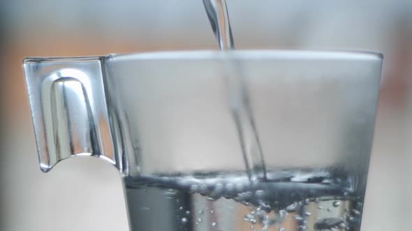 Hot water pouring in glass water slow motion
