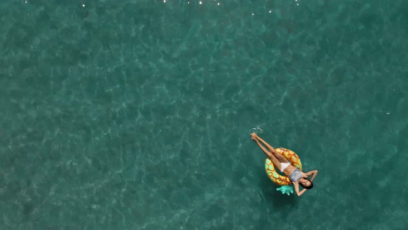 Aerial Top View of Calm Turquoise Sea Water and Beautiful Relaxed Woman Swimming on the Yellow alt