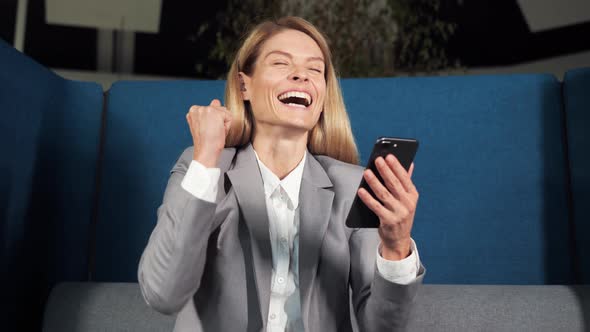 Happy Businesswoman Celebrating Online Victory Lottery on a Mobile Phone Winner alt