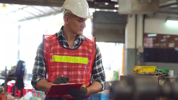 Caucasian engineer foreman writing on repair checklist of factory machine