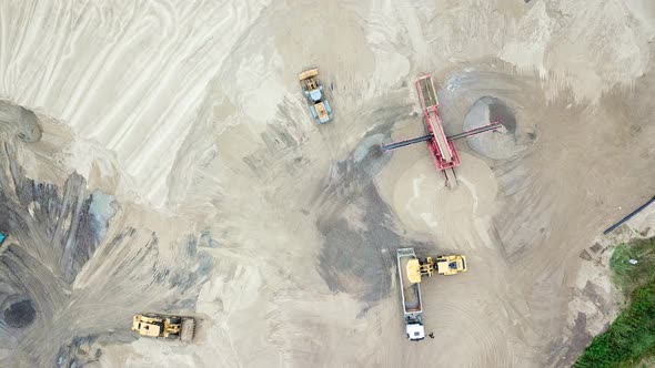 Excavator loader in sand quarry. View from above. Aerial view dumper trucks with cargo sand ridesing alt