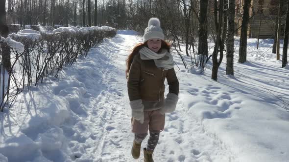 Happy Teenager Girl Jogging At Winter Sunny Day. Ginger-Haired  Girl Walking At Snowy Park