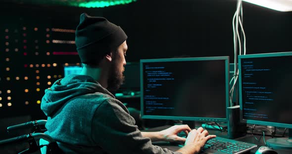Male Hacker Using Keyboard to Type a Dangerous Malware Into Bank System Hacker Breaks Into alt