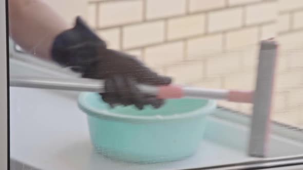 Man washes the windows with special foam and cleans them. Cleaning service. Worker in black gloves alt