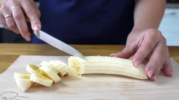 Woman Cutting Banana on Cutting Board Close Up alt