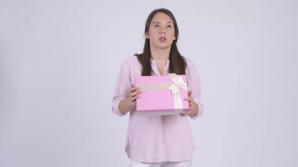 Young Multiethnic Businesswoman Thinking While Holding Gift Box alt