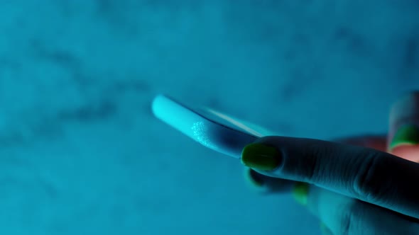 Woman Hands with Smart Phone Close Up in Trendy Neon Lights on Street alt