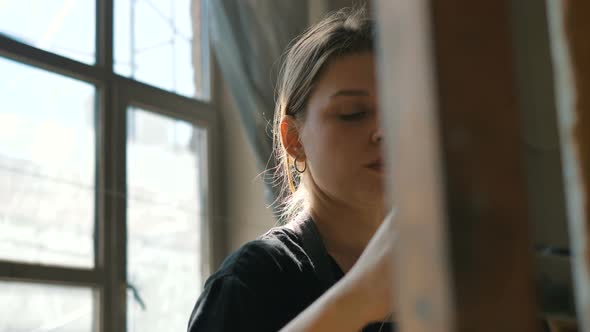 Female Artist Draws Picture with Brush in Sunny Art Studio alt