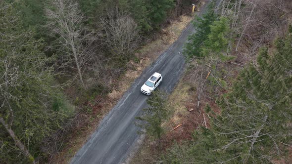 White suv car driving along tortuous mountain road. Aerial top-down view alt
