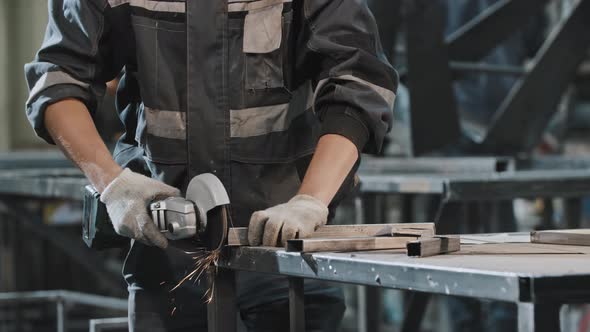 Young Man Working at the Construction Plant  Grinding the Cut on the Metal Detail alt