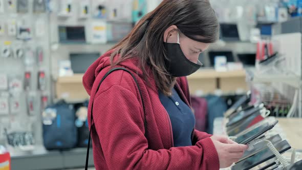 Girl in Mask Chooses Smartphone in Store Electronic Devices alt