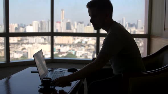 A Concentrated Young Businessman Is Working on a Laptop Computer Using His Notebook Sitting By the