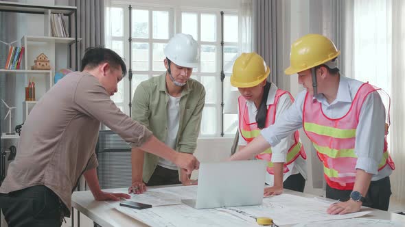 Three Asian Engineers With Helmets Using Laptop For Working To A Man At The Office alt