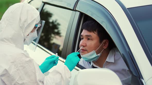 doctor in PPE suit test coronavirus(covid-19) to man in car by nasal swab cotton