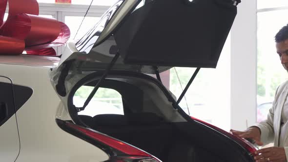 Handsome Mature Man Examining Trunk of a New Car at the Dealership alt