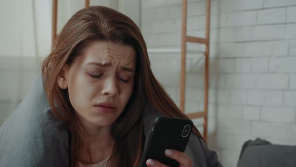 Desperate Young Lady Crying Looking At Cellphone In Bedroom Indoors alt