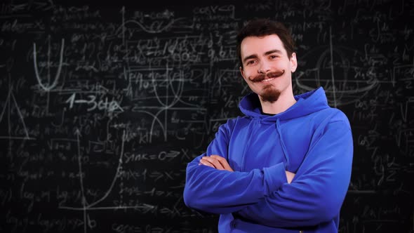 Portrait of a Young Bearded Student Who Stands at Background with Mathematical Formulas alt