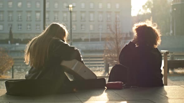 Teenage Girls Sitting on the City Embankment