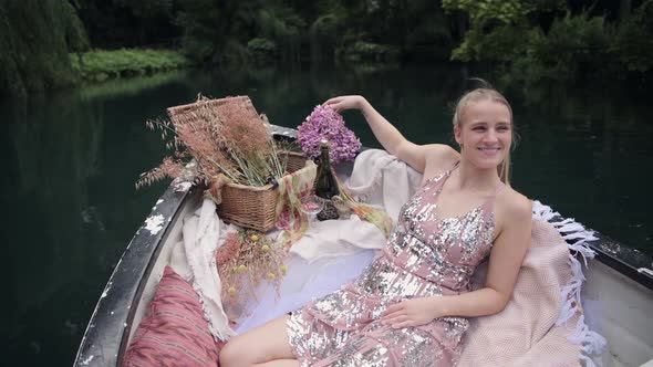Cute woman in rowboat turns head to partner and talks while looking at flowers on a romantic date on alt