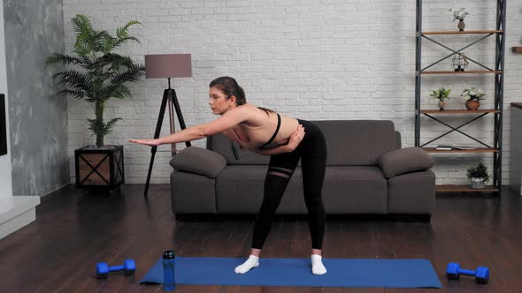 Young Fit Woman in Sportswear Doing Warmup Before Workout on Yoga Mat at Home alt