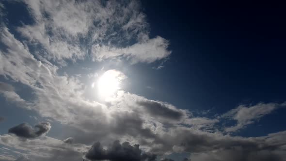 Time lapse: sun rays brake through fluffy clouds flying in the sky.