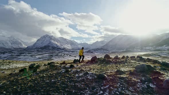 Male mountain climber raising hands with icepick on top of snowy peak. hiker at the top of a rock wi alt