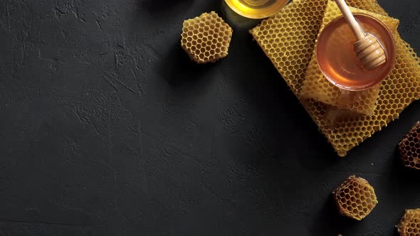 Honey dipper on the bee honeycomb on black table. Horizontal composition 4K UHD video footage alt