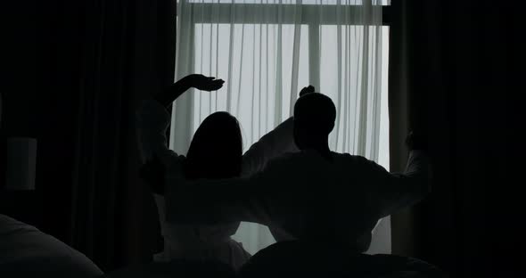 Silhouettes of Young Couple Stretching on Hotel Bed Backside