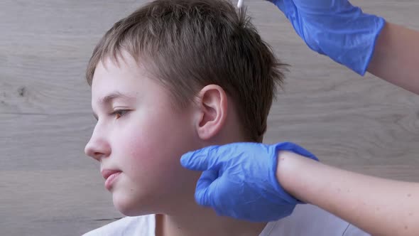 Doctor Otolaryngologist Cleans Ears Ear Canal of a Child with a Cotton Swab alt