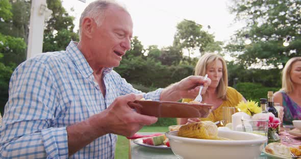 Grandfather feeding his grandson while having lunch outdoors alt