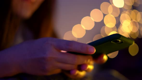 Asian woman using smart phone on the bed at night.