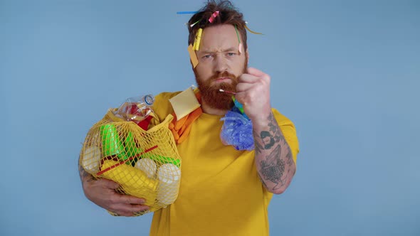 Man holding backage with trash and showing fist.