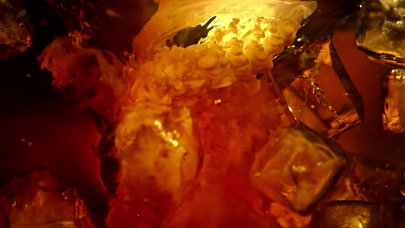 Super Slow Motion Shot of Pouring Cream Into Cold Coffee Whirl with Ice Cubes at 1000Fps alt