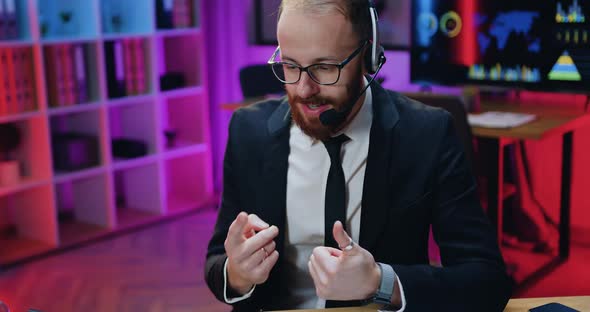 Manager in Glasses Wears Headset During Video Conference on Computer in Evening Office alt