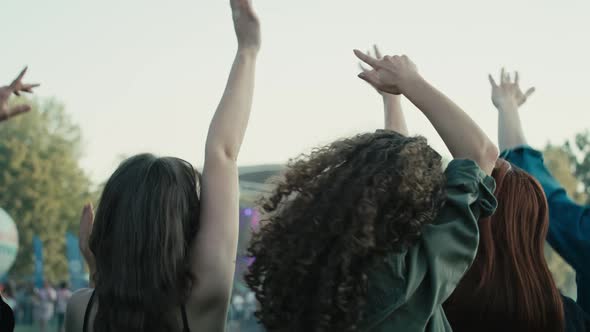Rear view of friends dancing on music festival with hands up. Shot with RED helium camera in 8K. alt