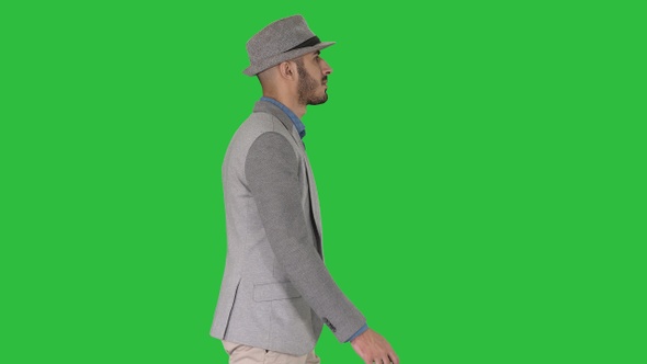 Casual arabic man in hat walking on a Green Screen, Chroma Key. alt