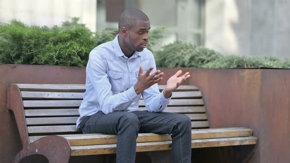 Worried Young African Man Sitting Outdoor and Thinking  alt