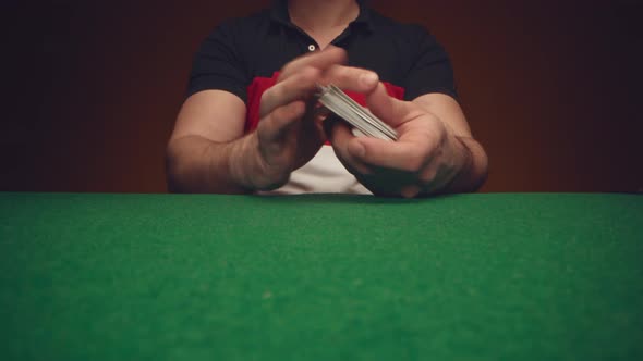 Male Hands Shuffle a Deck of Playing Cards Above Poker Table
