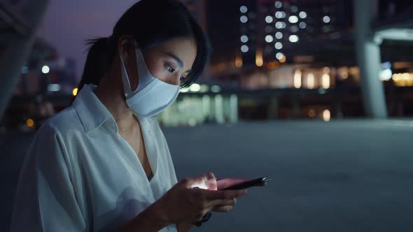 Young Asia businesswoman in fashion clothes wearing face mask using smart phone typing text message.