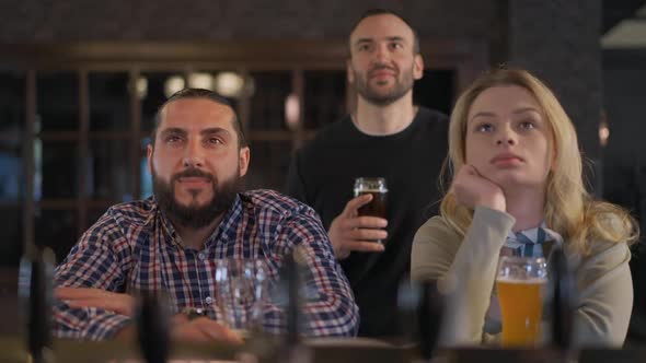 Group of Friends Watching Sports Match Sitting in Pub at Bar Counter alt