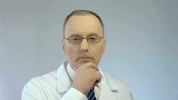 Doctor Looking Concerned, Kind Smile Appears on Man's Face as He Finds Solution alt