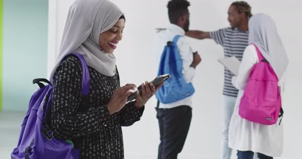African Female Student with Group of Friends in Background Wearing Traditional Islamic Hijab Clothes