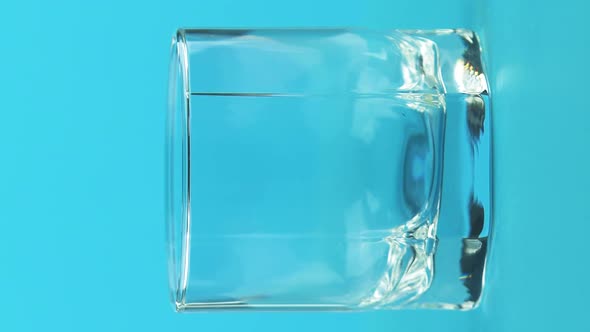 Vertical Video Closeup Shot of Milk Cold Beverage Drink Pooring Into Low Glass with Facets Blue