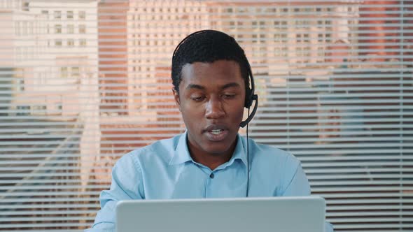 Black Man in Headset Speaking with Somebody and Working on the Computer