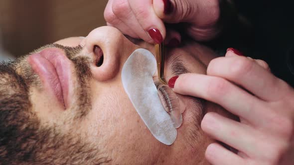 Beautician with Special Tweezers Evenly Smoothes Eyelashes on Silicone Poller alt