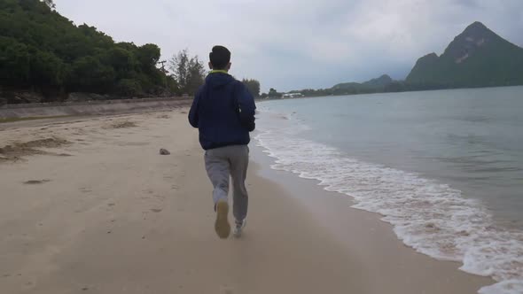 Handsome man running on the beach, Sportsman stretching running along the beach before sunset.