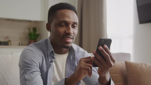 Africanamerican Adult Man Thinking and Typing a Reply with Smile on His Smartphone alt