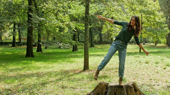 Young woman balancing on tree trunk in park