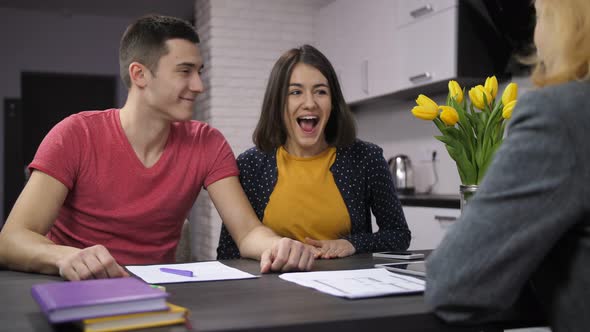 Cheerful Couple Signing Contract with Estate Agent alt